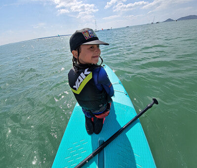 Child wearing a Yak Delta buoyancy aid on a paddleboard