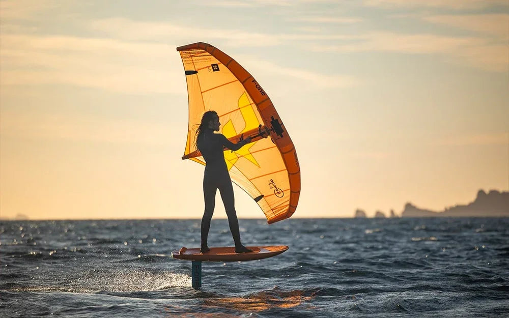 F-One Swing V2 Action wing used for wing foiling on water at sunset