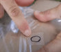 Clear kitesurfing bladder repair patch being applied to a surface by hand