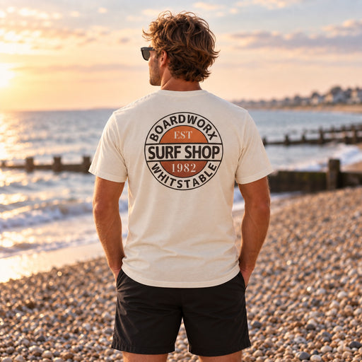 Man wearing the Boardworx Surf Shop ivory white T-shirt on a Whitstable shingle beach, back logo view