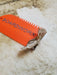 Bright orange BOARDWORX surf wax comb scraper with wax residue on a surfboard