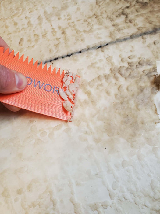 Orange wax comb scraping surfboard wax, close-up on textured surfboard surface