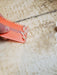 Orange wax comb scraping surfboard wax, close-up on textured surfboard surface
