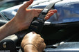 Bulldog black roof rack tie-down strap securing surfboard on car for watersports.