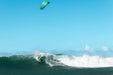 Duotone Neo SLS teal kitesurfing kite in action on ocean waves under clear sky