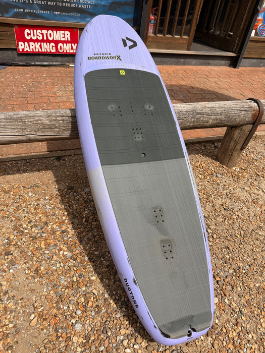 Full deck top-down view of used Duotone Skybrid 100L 2025 wing foil board showing grey EVA traction pad and footstrap insert positions