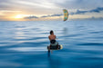 Man kitesurfing on Duotone foil board with yellow kite over calm blue sea at sunset