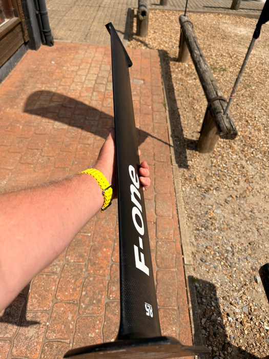 Full length side profile of used F-one Carbon Mast 85 held up showing clean carbon body with F-one branding and 85 size marking