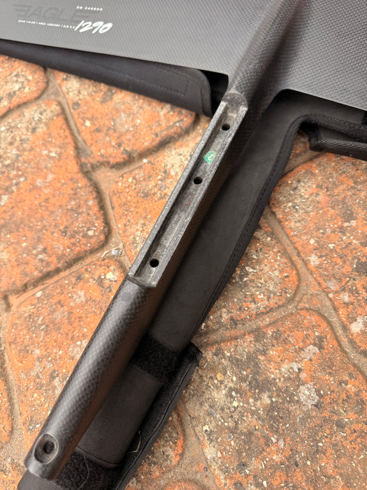 Close-up of F-one Eagle 1290 Titan connection plate showing hardware detail and protective carry bag