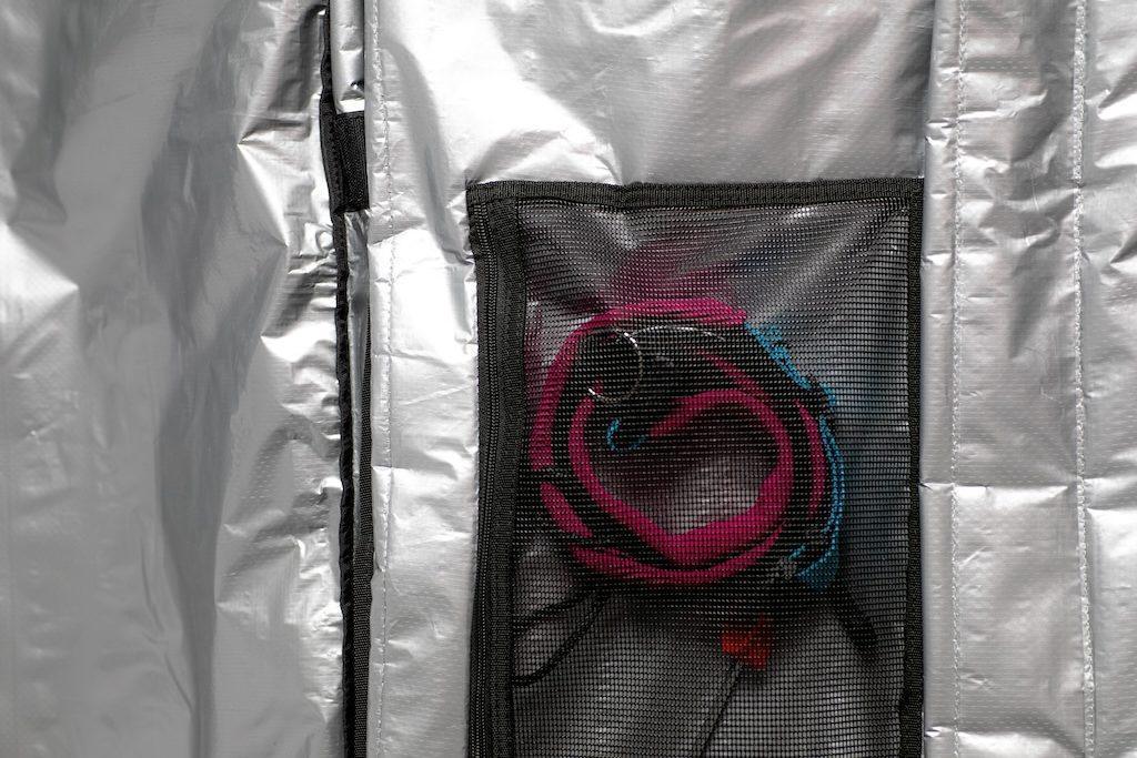 Mid-length down wind travel bag interior with mesh pocket and rolled pink-blue strap