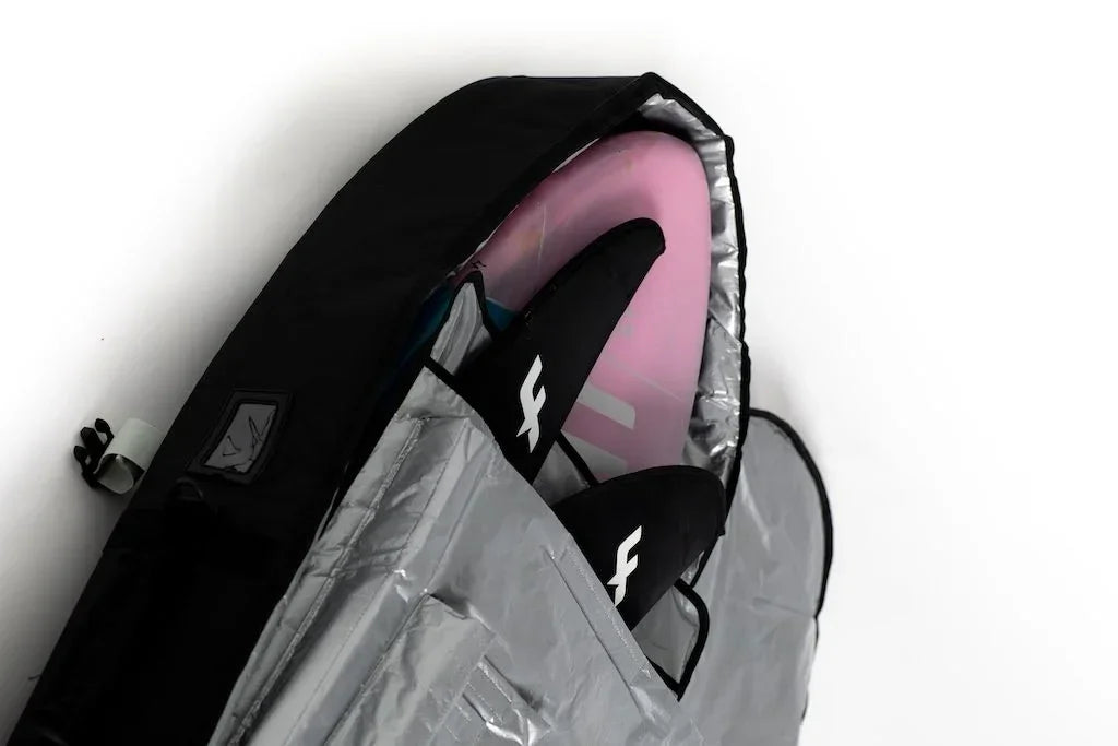 Mid-length black travel board bag with pink surfboard and black fins inside, silver lining visible