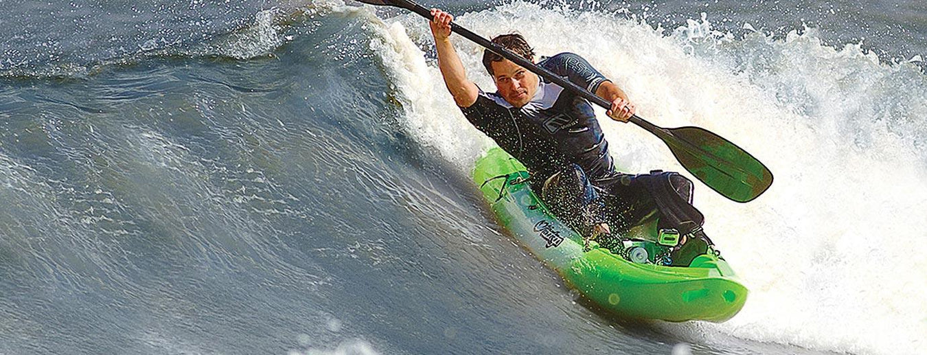 Tootega kayak in green ridden by a kayaker surf paddling on a wave