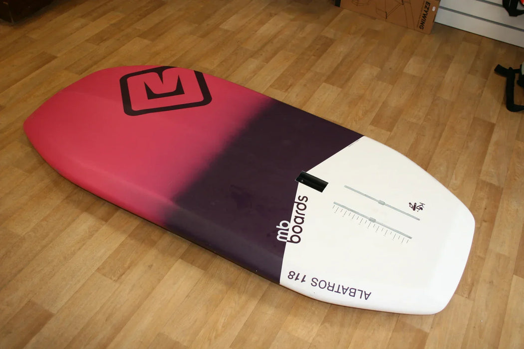 MB Boards Albatros 118L wingfoil board with pink, purple, and white design on wood floor.