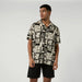 Beige short sleeve surf shirt with black abstract print, worn with black board shorts