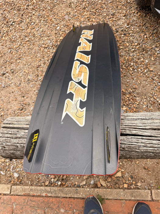 Naish Monarch black kitesurfing kiteboard with yellow graphics on pebbled ground