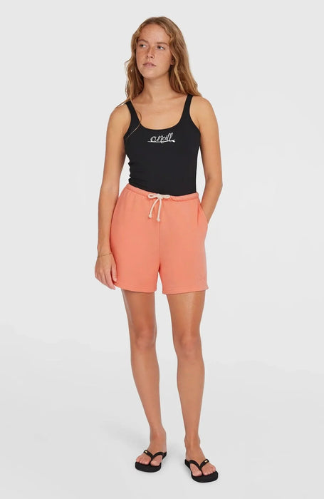 Woman wearing O'Neill black tank top and coral pink drawstring sweatshorts