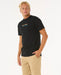 Rip Curl black t-shirt with rainbow logo, surf clothing, worn by man in beige shorts
