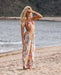 Rip Curl Cala Vadella floral beach pants with colorful pattern, worn by woman on sandy shore