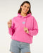 Rip Curl pink surf hoodie with logo, worn by woman, paired with denim shorts