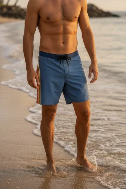 Rip Curl Mirage Pacific men's blue board shorts with side stripes, beach setting