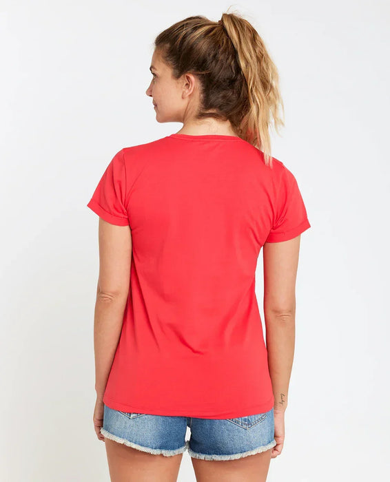 Woman wearing Rip Curl hibiscus red V-neck tee and denim shorts, back view.