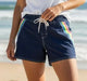Rip Curl Surf Side 5 dark navy boardshorts with rainbow side stripes, worn at the beach