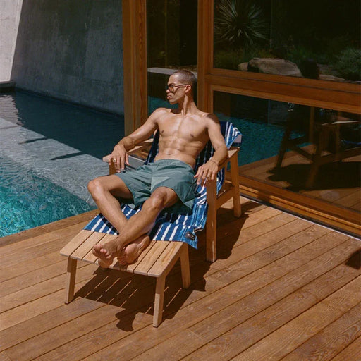 Man relaxing in green board shorts by poolside, ideal for watersports and beachwear