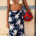 Slowtide Luca beach towel with navy palm tree print, woman in bikini holding red ball