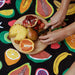 Slowtide Ripe beach towel with colorful fruit print, wooden board with fresh fruit