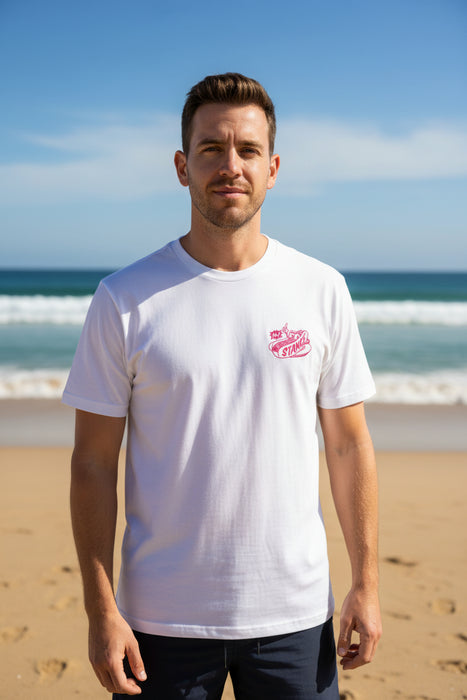 Man wearing white Stance dog tee with pink logo on beach, surf and watersports apparel