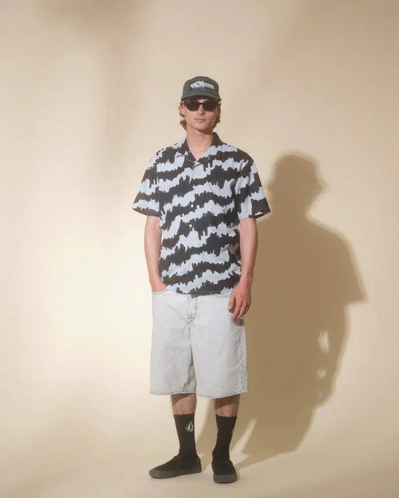 Man wearing Volcom Carolina Blue patterned short sleeve shirt, denim shorts, black socks, and cap